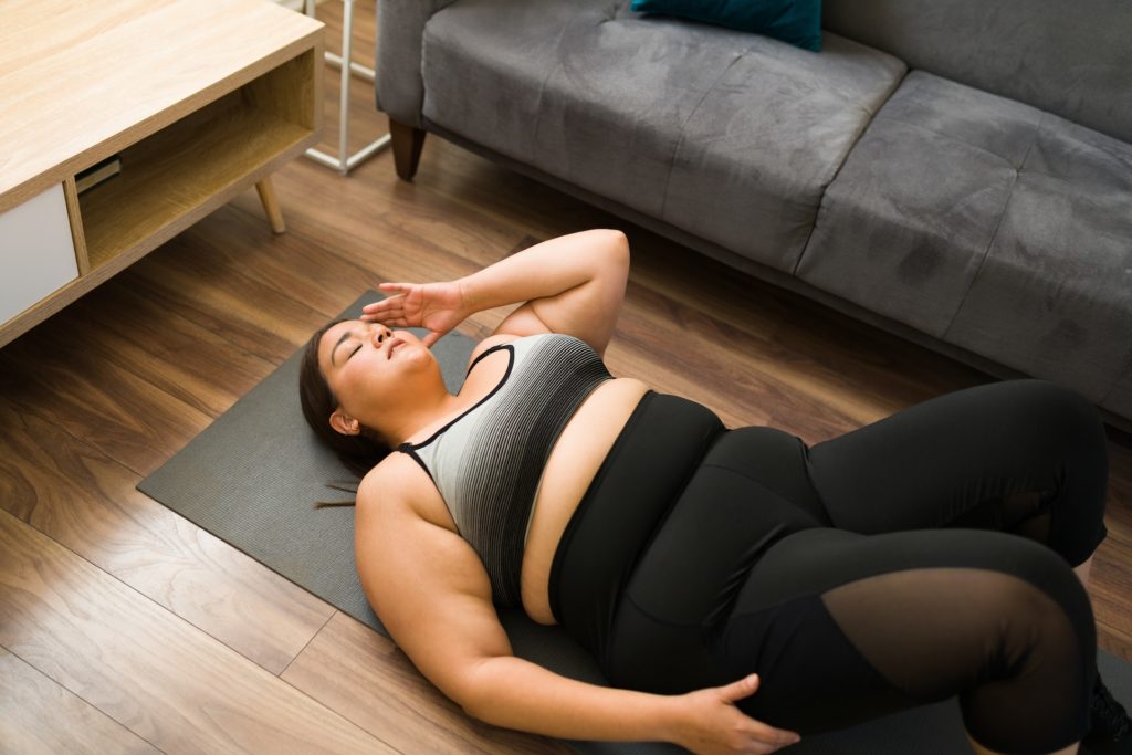 Une personne en surpoids sur un tapis de yoga.