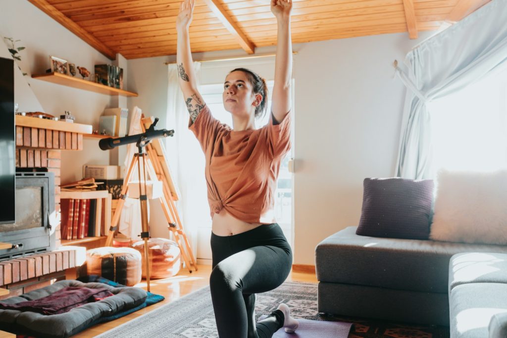 Une pratiquante de yoga s'entraîne dans son salon.