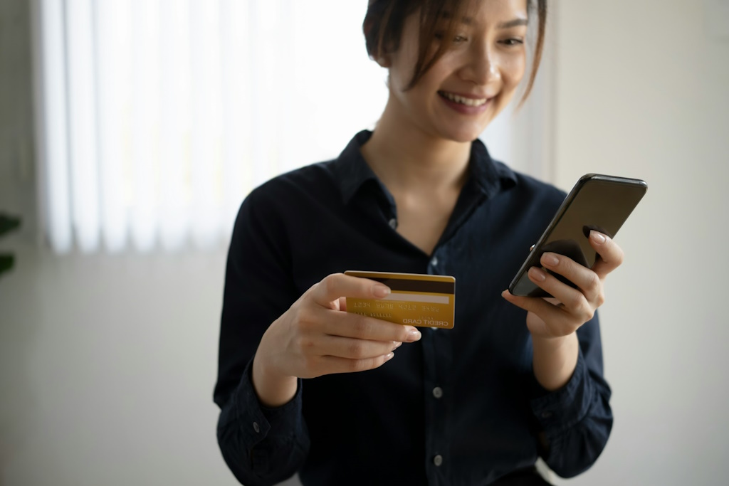 Une dame sourie en payant avec une application mobile.