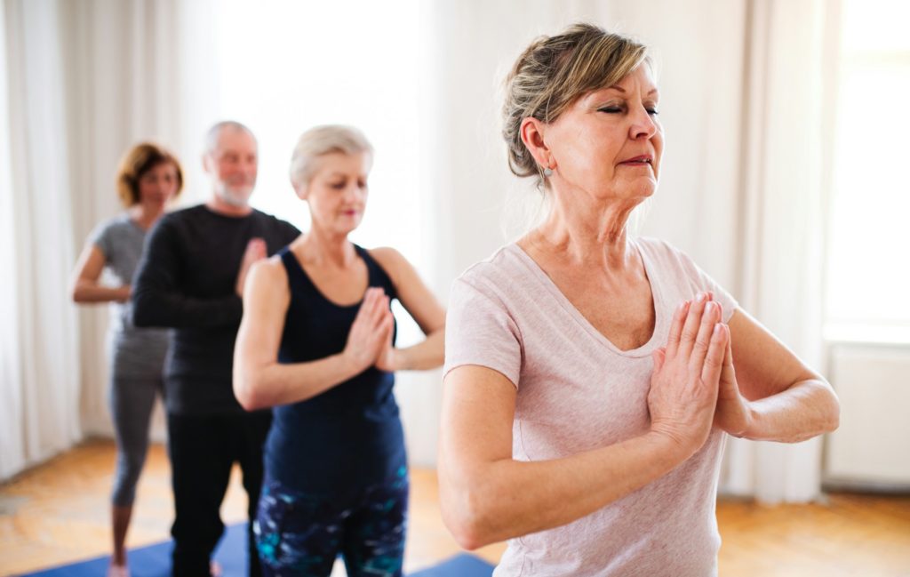 Quatre personnes font une position de yoga en file indienne.