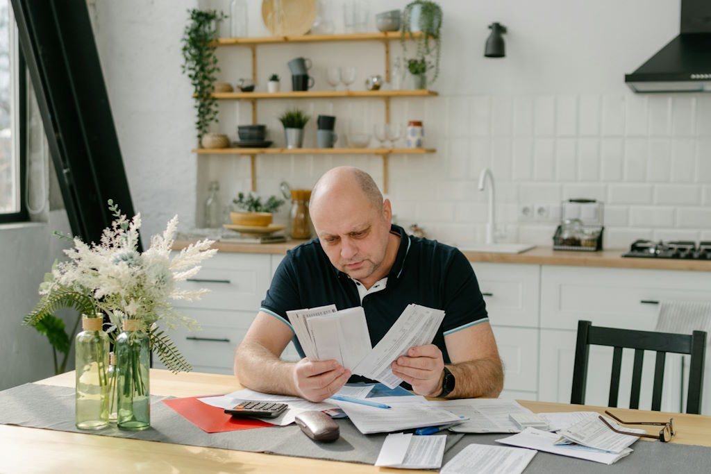 Un adulte assis à table, semble surpris par le contenu d'une feuille de papier.