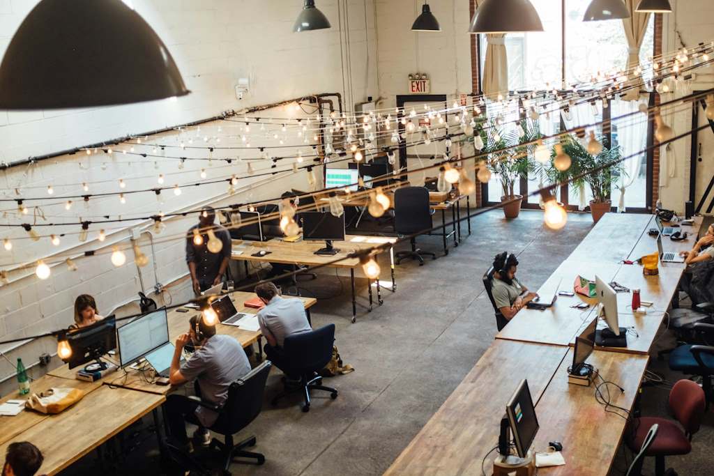 Un open-space d'entreprise vu depuis le plafond avec les luminaires et les salariés.