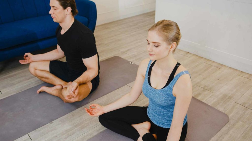 Deux personnes effectuant une posture de yoga et méditant.