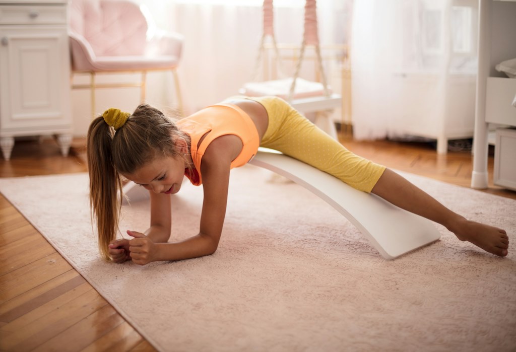 Une fille s'étire et fait la planche au sol.