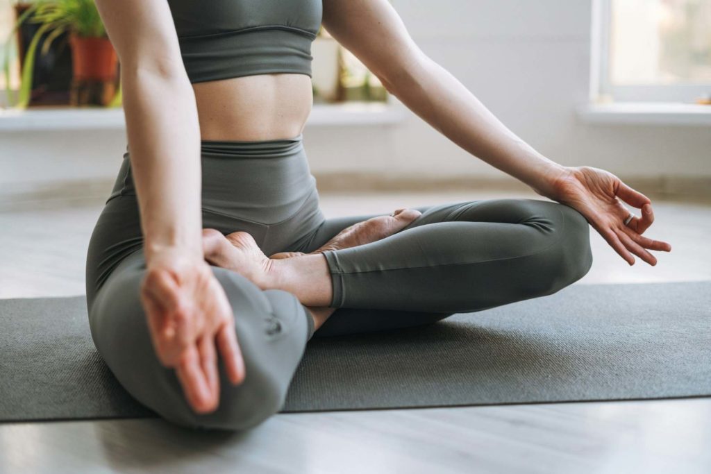 Vue d'une sportive assise en position de lotus et pratiquant la méditation.