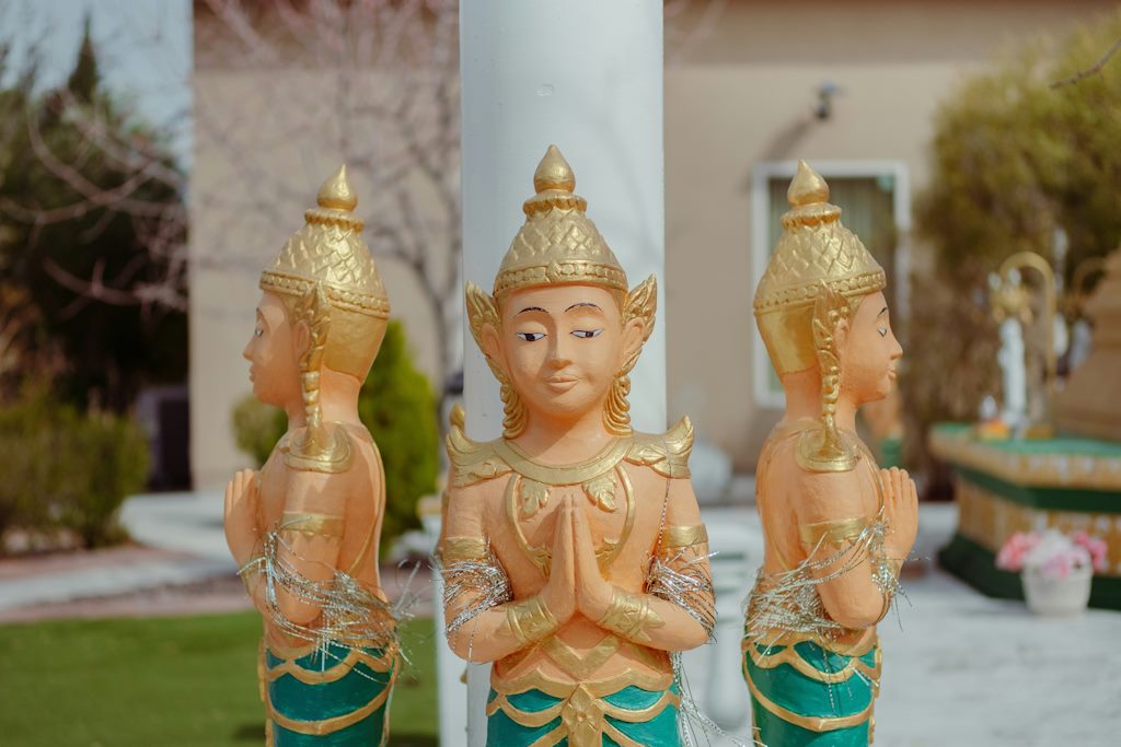 Des statues qui font une posture de yoga autour d'un pilier de bâtiment.