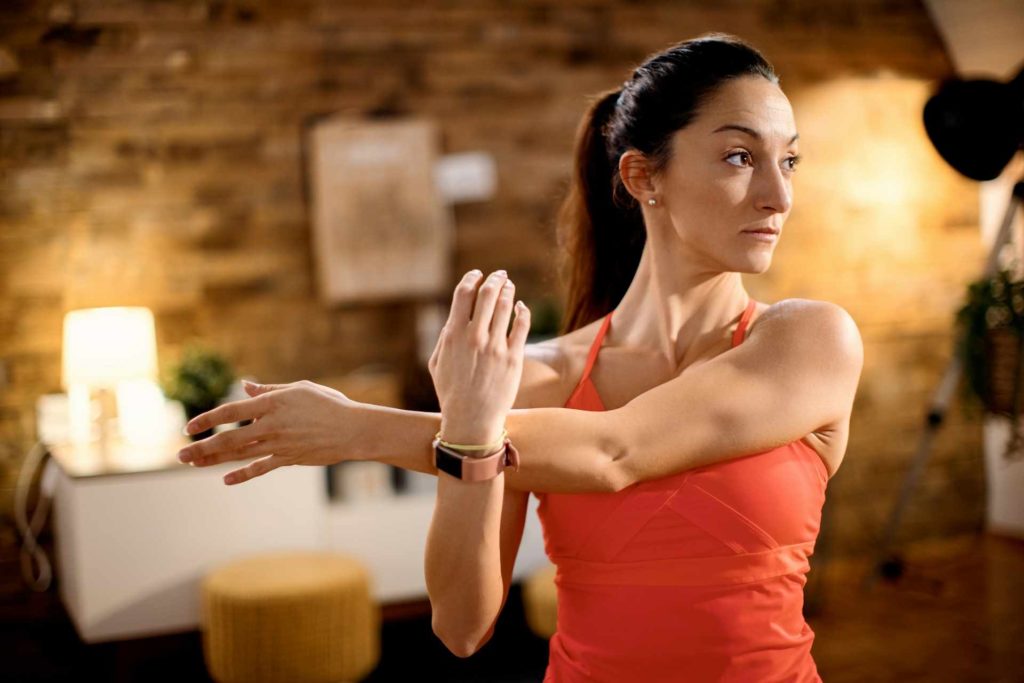 Une femme effectue un exercice d'étirement dans une maison en pierre.