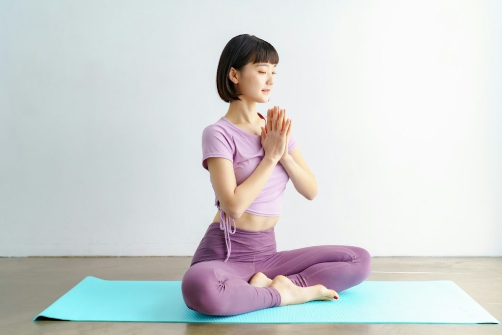 Une pratiquante de yoga fait une posture sur un tapis vert.