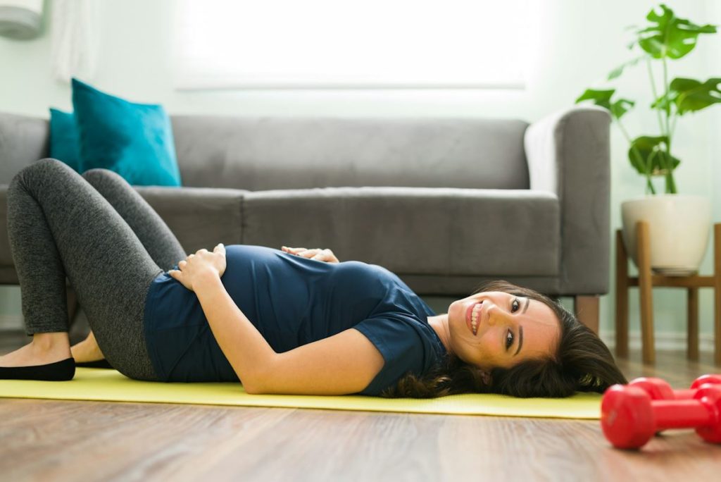 Une femme allongée au sol fait du yoga pour femme enceinte.