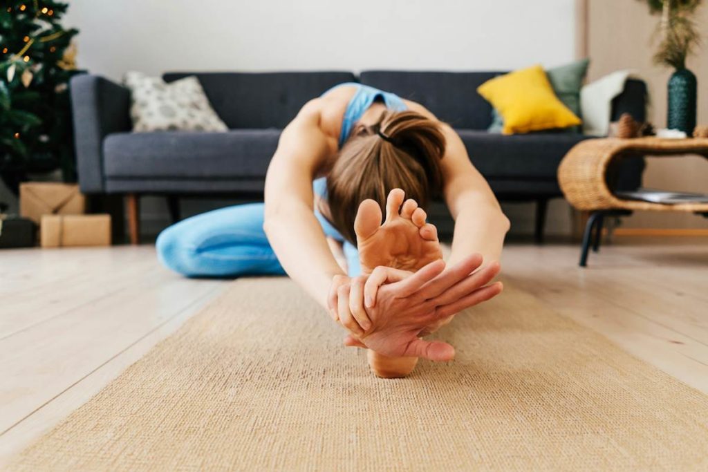 Une pratiquante de yoga tend ses bras vers ses pieds au sol.