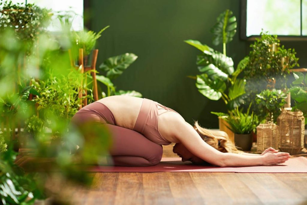 Une pratiquante de yoga effectue une posture de l'enfant.
