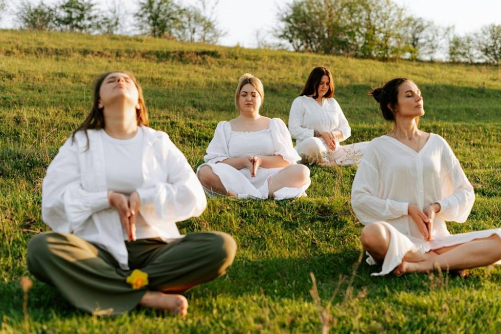 Quatre pratiquantes de yoga s'entraînent à l'extérieur.