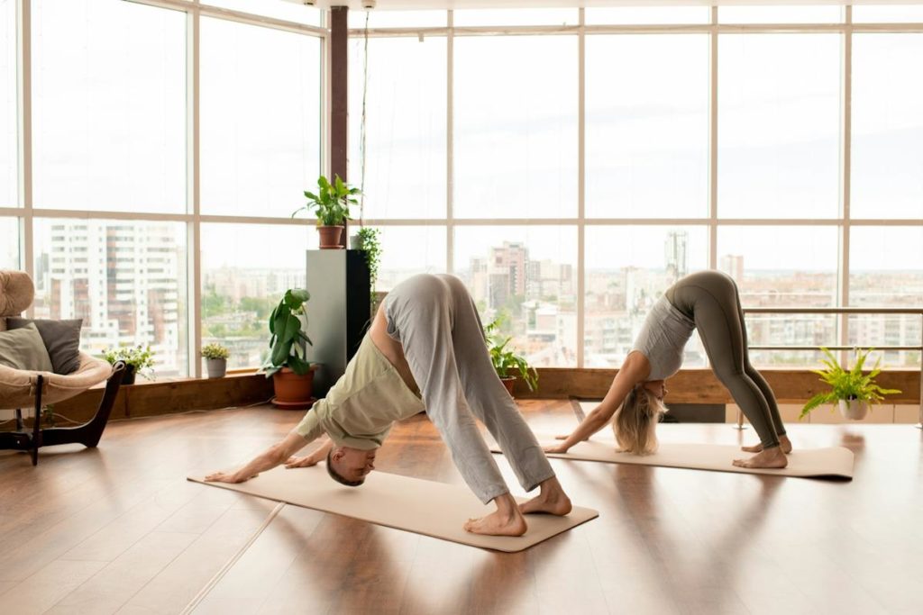 Une femme et un homme font du yoga dans une salle lumineuse.