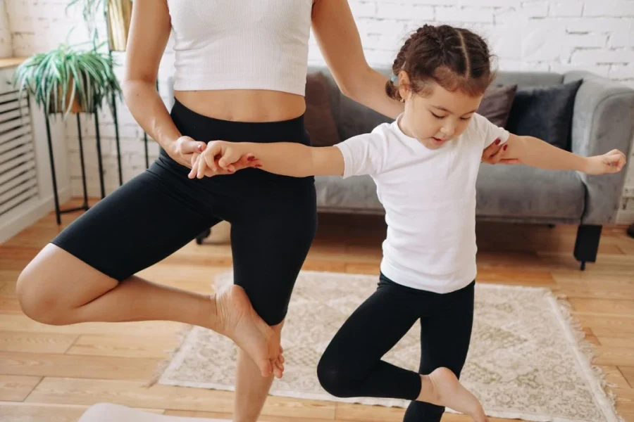 Une mère aide son enfant à faire une posture de yoga.