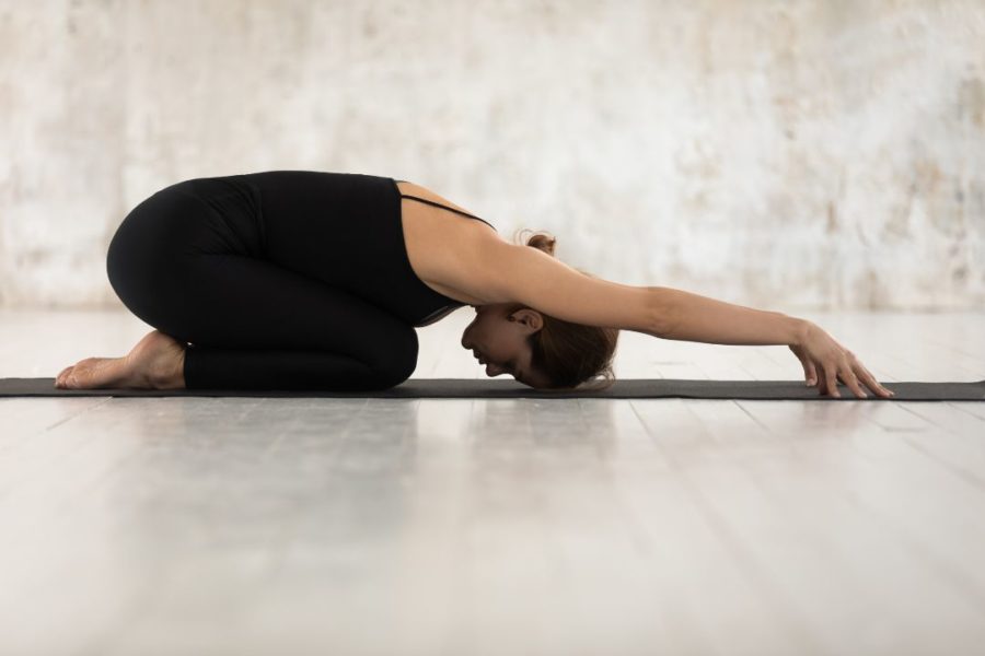 Une pratiquante de yoga effectue une posture simple au sol, les bras tendus.