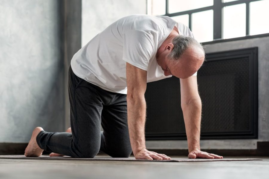 Un pratiquant de yoga au sol s'étire le dos.