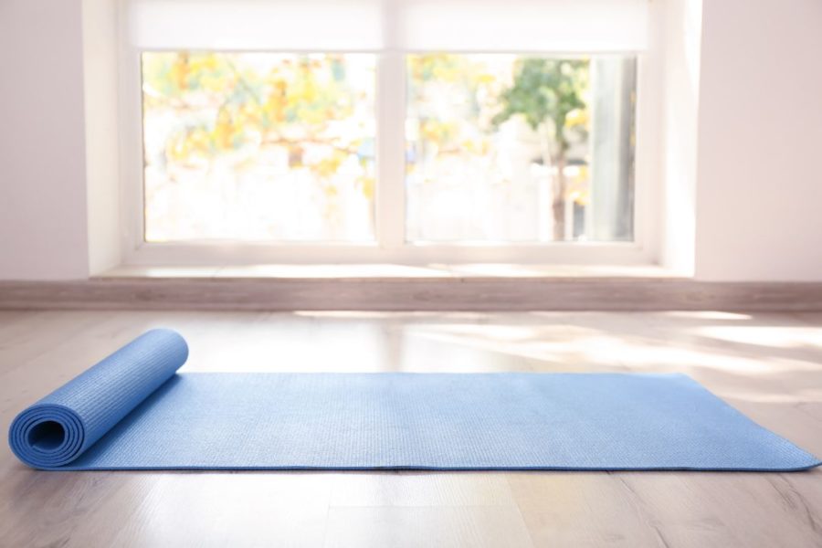 Vue d'un tapis de yoga déroulé au sol dans une pièce lumineuse.