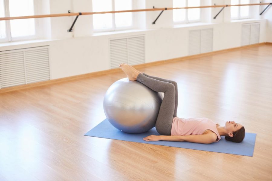 Une personne en train de s'étirer le dos sur son ballon de Pilates.