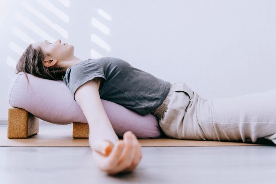 Un femme s'étire le dos, soutenu par son coussin de yoga.